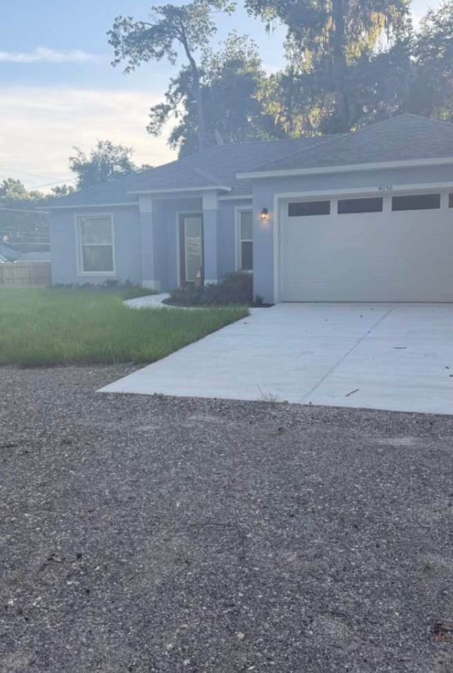 Before — a new-build house with the front yard grown up tall against the driveway and walk.