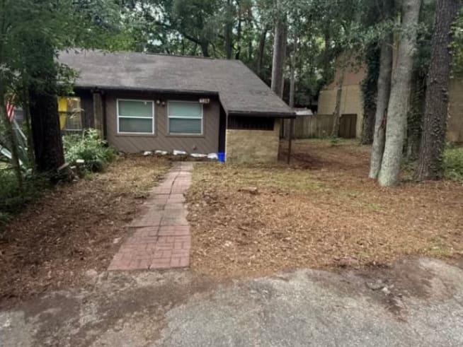 After — the same yard cleared to bare ground, with the brick walk uncovered end to end.